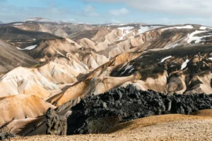 Black lava fields contrasting with colorful rhyolite mountains in Kerlingafjöll, Iceland