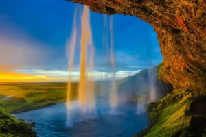 View from behind Seljalandsfoss waterfall on Iceland’s South Coast during sunset