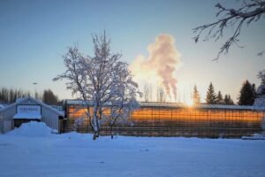 Friðheimar greenhouse glowing warmly in winter snow at sunset in South Iceland