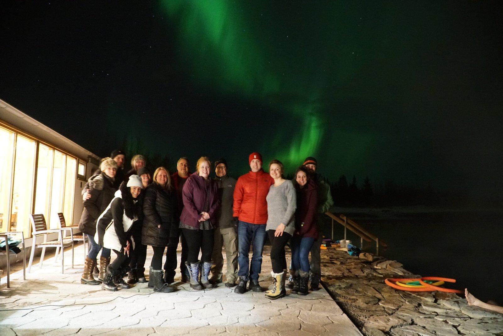 Group of travelers posing together under the northern lights in Iceland