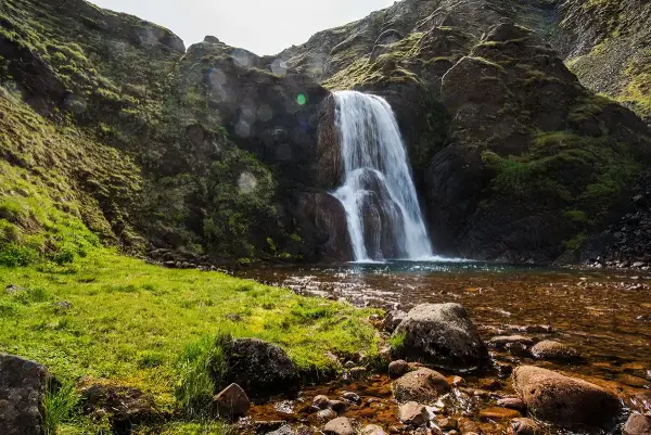 Helgufoss waterfall in a green valley near Mosfellsdalur, Iceland