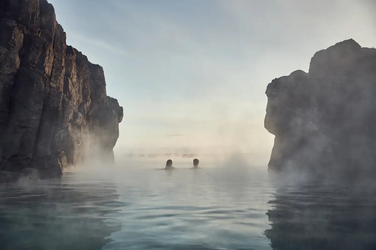 Visitors relaxing in Sky Lagoon infinity pool between lava cliffs in Iceland