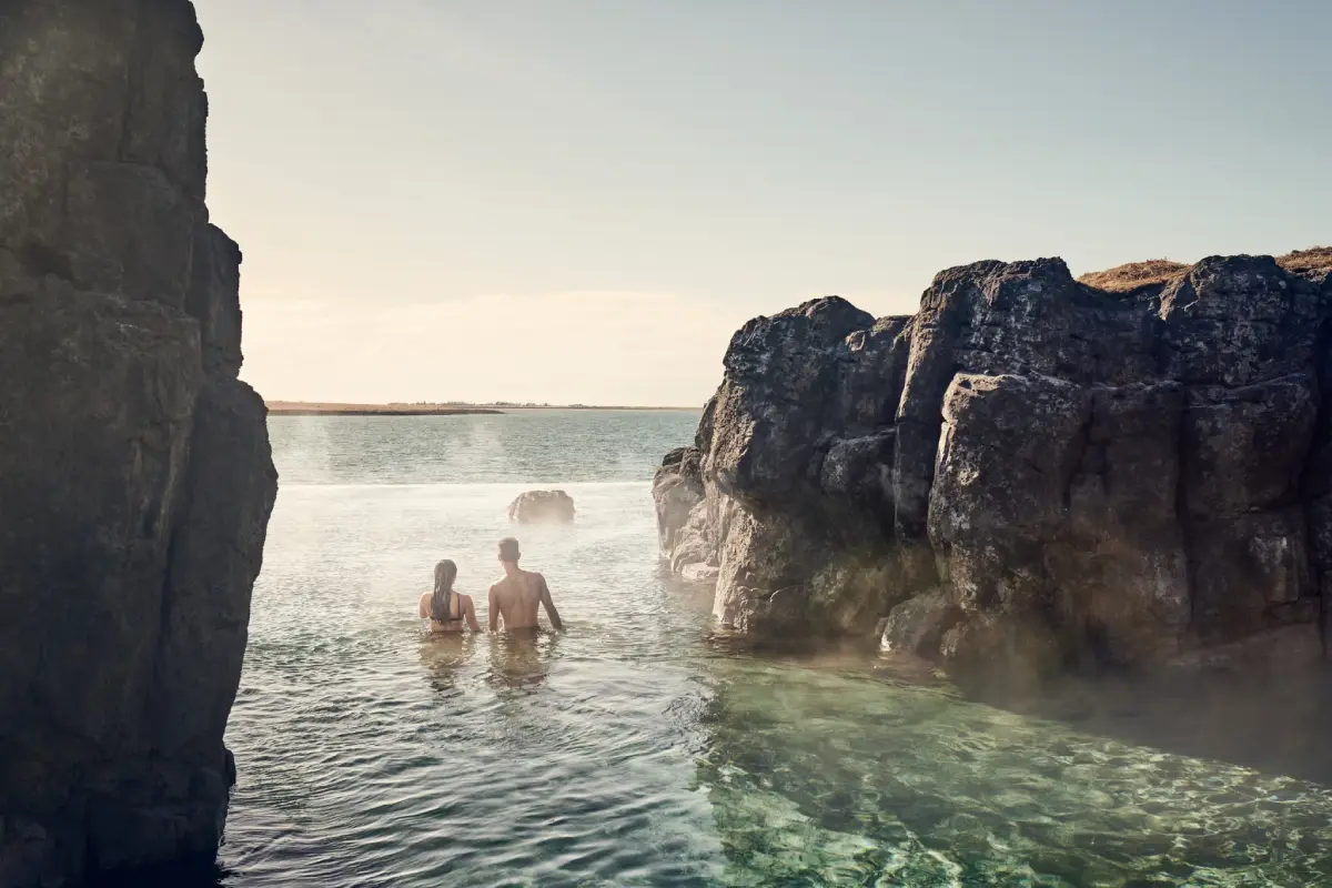 A couple bathing in Sky Lagoon geothermal spa surrounded by lava cliffs