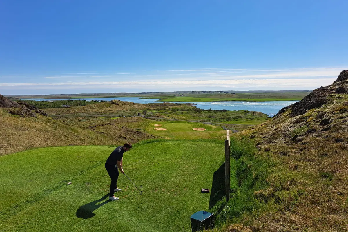 Golfer teeing off at Kiðjaberg Golf Course with panoramic Icelandic scenery