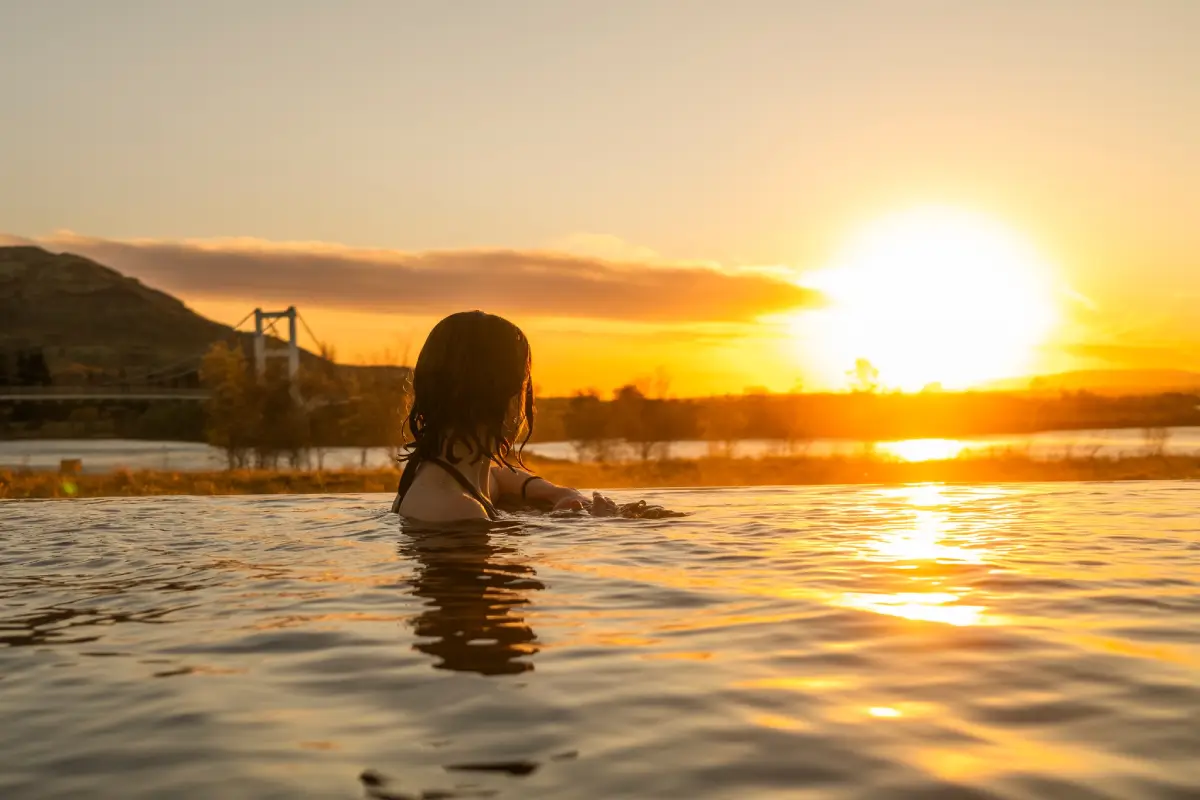 A woman relaxing in Laugarás Lagoon geothermal pool at sunset in South Iceland