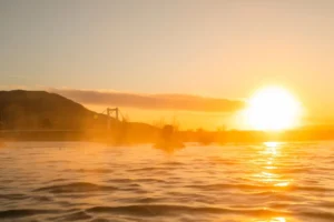 A visitor bathing in Laugarás Lagoon's outdoor hot pool during sunset