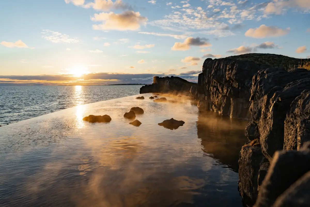 Sunset over Sky Lagoon infinity pool with steam and ocean views