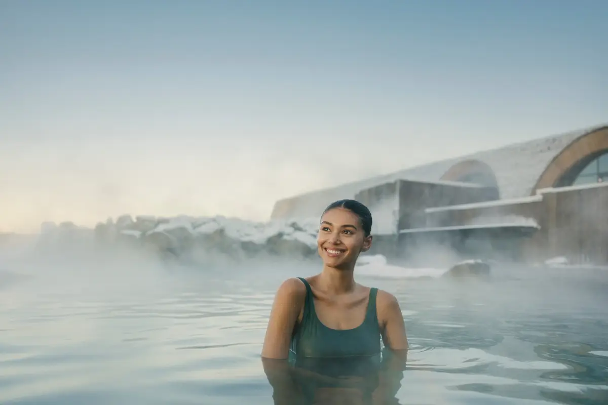 A woman relaxing in the Laugarás Lagoon geothermal spa in Iceland with steam rising around her