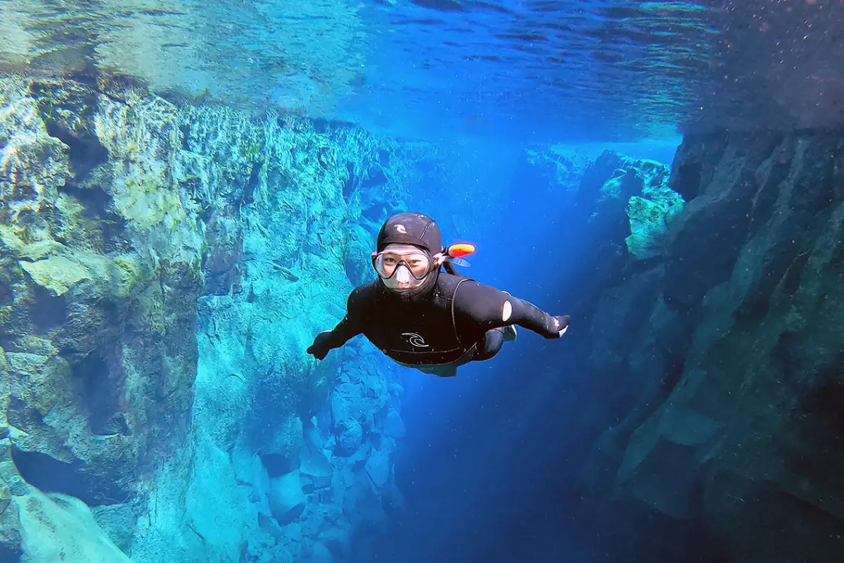 Snorkeler swimming in clear blue water in Silfra Fissure between tectonic plates in Iceland