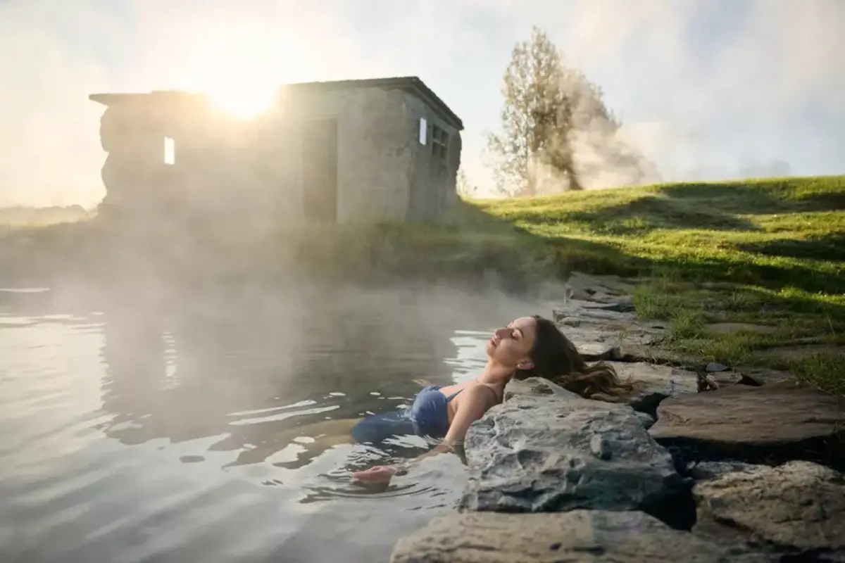 Woman relaxing in the Secret Lagoon geothermal pool in Flúðir, Iceland at sunset