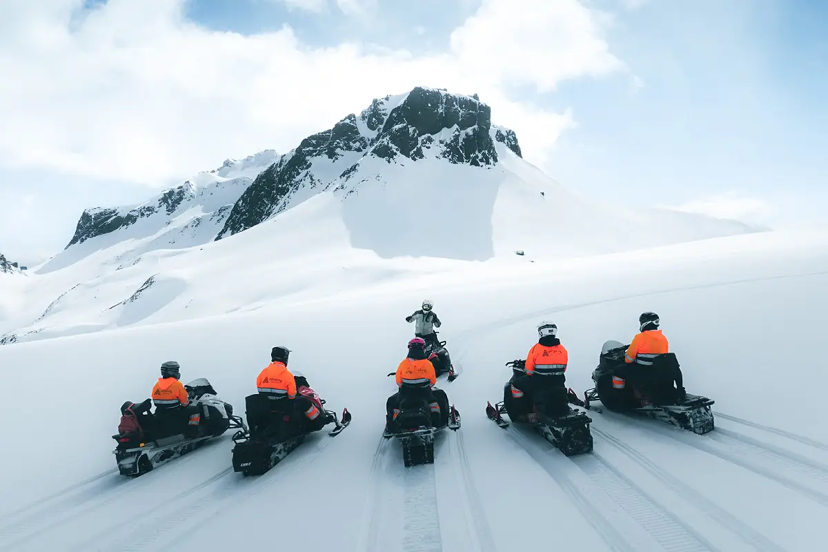 Group snowmobiling on Langjökull Glacier in Iceland with mountains in the background