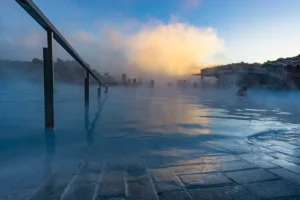 Visitors relaxing in the Blue Lagoon geothermal spa in Iceland with steam rising at sunset