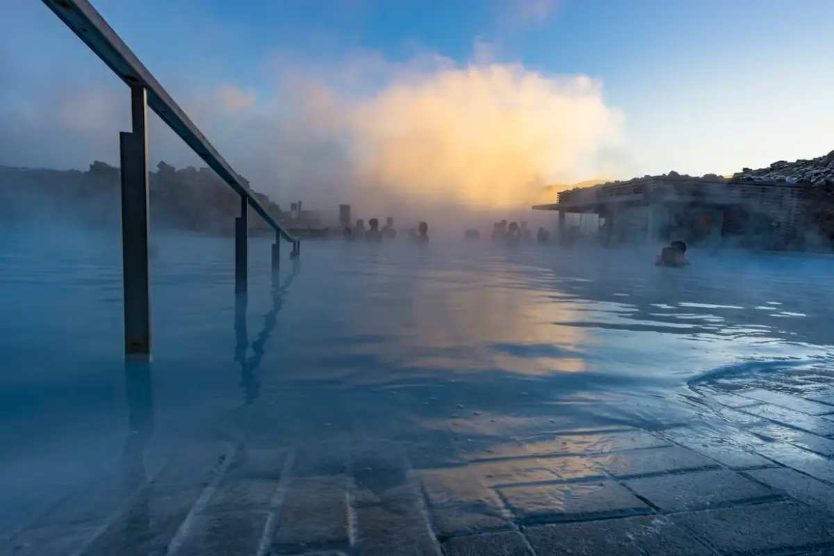 Visitors relaxing in the Blue Lagoon geothermal spa in Iceland with steam rising at sunset
