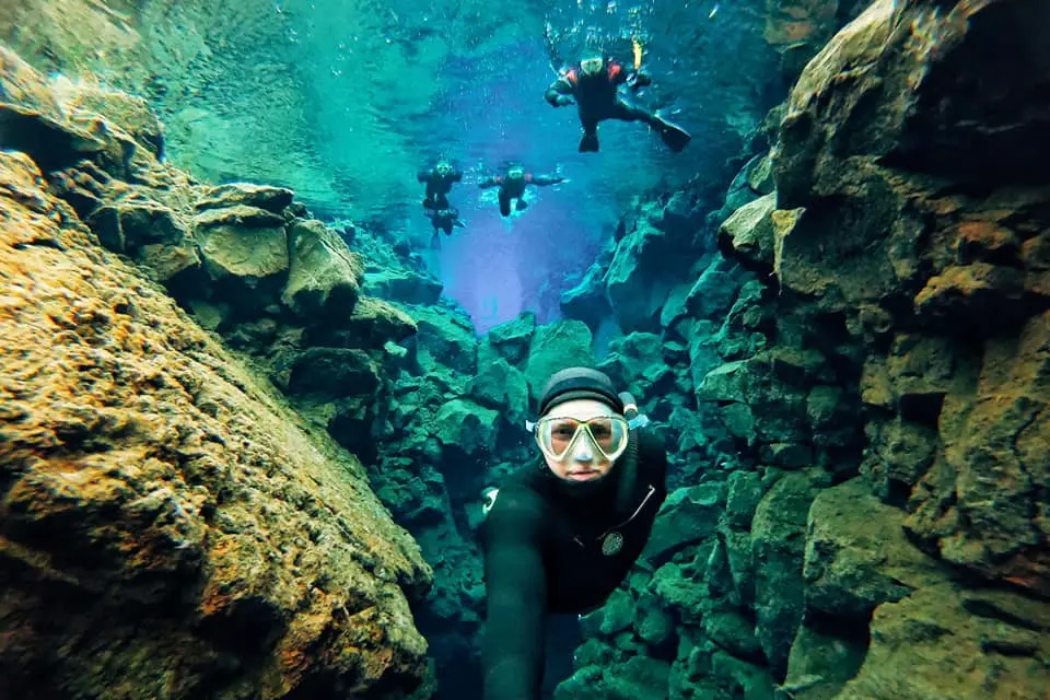 Group of people snorkeling in Silfra Fissure at Þingvellir National Park in Iceland