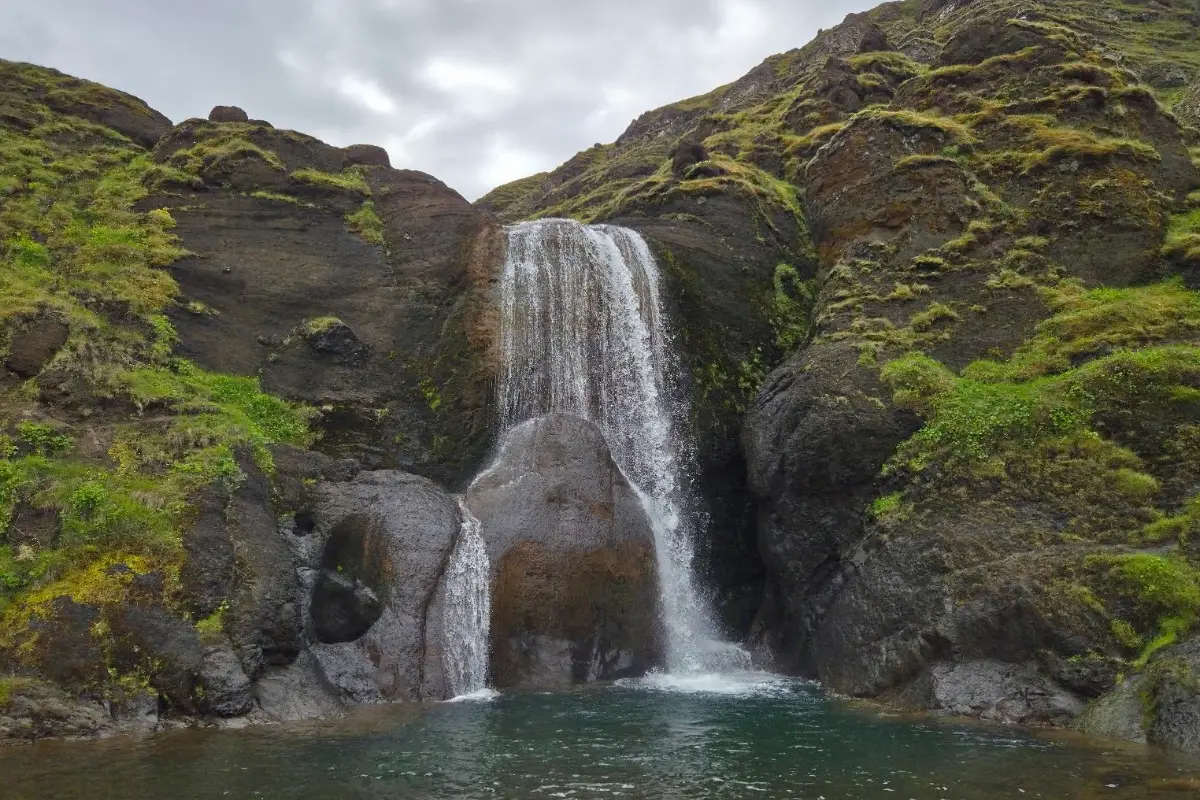 Helgufoss waterfall surrounded by basalt cliffs and mountain scenery
